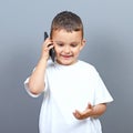 Cute little boy kid talking on cellphone against gray background Royalty Free Stock Photo