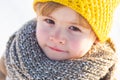 Cute little boy kid in winter clothes walking under snow. Child in blue jacket and yellow hat walks in snow-covered Royalty Free Stock Photo