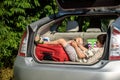 Cute little boy laying on the back of the bags and baggage in the car trunk ready to go on vacation with happy expression. Kid Royalty Free Stock Photo