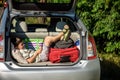 Cute little boy laying on the back of the bags and baggage in the car trunk ready to go on vacation with happy expression. Kid Royalty Free Stock Photo