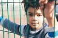 Little boy leaning at the metal fence of the playground Royalty Free Stock Photo