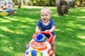 Cute little boy learning to walk with walker toy on green grass lawn at backyard. Baby laughing and having fun making Royalty Free Stock Photo