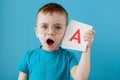 Cute little boy with letter on blue background. Child learning a letters. Alphabet Royalty Free Stock Photo