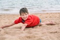 Cute little boy lies on the sand on the seashore happy, Royalty Free Stock Photo