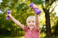 Cute little boy lifting dumbbells outdoors Royalty Free Stock Photo