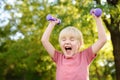 Cute little boy lifting dumbbells outdoors Royalty Free Stock Photo