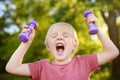 Cute little boy lifting dumbbells outdoors Royalty Free Stock Photo