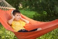 Cute little boy listening to music while relaxing in hammock on summer day Royalty Free Stock Photo