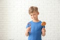 Cute little boy with lollipop and candy cane near white brick wall Royalty Free Stock Photo