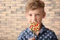 Cute little boy with lollipop near brick wall Royalty Free Stock Photo