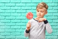 Cute little boy with lollipop near color brick wall Royalty Free Stock Photo