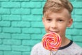 Cute little boy with lollipop near color brick wall Royalty Free Stock Photo