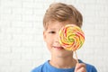 Cute little boy with lollipop near white brick wall Royalty Free Stock Photo