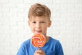 Cute little boy with lollipop near white brick wall Royalty Free Stock Photo