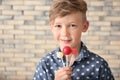 Cute little boy with lollipops near brick wall Royalty Free Stock Photo