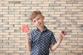 Cute little boy with lollipops near brick wall Royalty Free Stock Photo