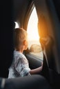 Cute little boy looking out of window of a car during sunset on the beach Royalty Free Stock Photo