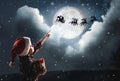 Cute little boy looking at Santa Claus with reindeers in sky on full moon night. Christmas holiday Royalty Free Stock Photo