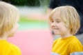 Cute little boy looks in distorting mirror in play center. Child playing on outdoor playground