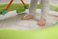 Cute little boy making first steps with baby walker on wooden floor, closeup