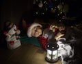 cute little boy in New Year's pajamas sleeps under a decorated Christmas tree