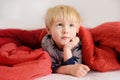 Cute little boy in pajamas having fun in bed after sleeping and watching TV or dreaming Royalty Free Stock Photo