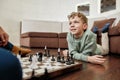 Cute little boy playing chess with grandfather while lying on the floor in the living room, spending time together at Royalty Free Stock Photo