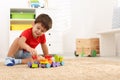 Cute little boy playing with colorful toys on floor at home, space for text Royalty Free Stock Photo