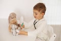 Cute little boy playing doctor at home and curing plush toy. Sweet toddler child plays indoor. Having fun. Kids and Royalty Free Stock Photo