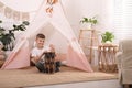 Cute boy playing drum near toy wigwam at home Royalty Free Stock Photo