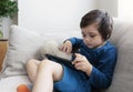 Cute little boy playing game on tablet, Child watching cartoons on digital taplet, Kid sititng on sofa with curious face playing g Royalty Free Stock Photo