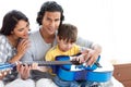 Cute little boy playing guitar with his parents Royalty Free Stock Photo
