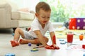 Cute little boy playing with paints on floor in room Royalty Free Stock Photo