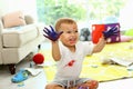 Cute little boy playing with paints on floor in room Royalty Free Stock Photo