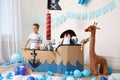 Cute little boy playing with pirate cardboard ship and toys at home. Child`s room interior Royalty Free Stock Photo