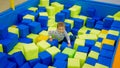 Cute little boy playing in popl full of soft cubes in palyroom