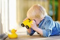 Cute little boy playing with rubber duck and plastic binoculars outdoors