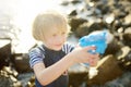 Cute little boy playing with water pistol on the seashore on a hot day. The child having fun with water gun outdoors during the Royalty Free Stock Photo