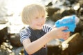 Cute little boy playing with water pistol on the seashore on a hot day. The child having fun with water gun outdoors during the Royalty Free Stock Photo