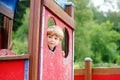 Cute little boy pretends driving an imaginary car on kids playground, outdoors. Preschool child play outdoors. Kid