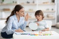 Cute little boy pronouncing sound O looking at mirror, professional woman therapist teaching kid right pronounciation Royalty Free Stock Photo