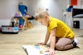 Cute little boy reading a book on the floor in a kindergarten. The child has time in the preschool Royalty Free Stock Photo