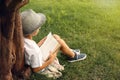 Cute little boy reading book on green grass near tree in park Royalty Free Stock Photo