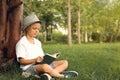 Cute little boy reading book on green grass near tree in park Royalty Free Stock Photo