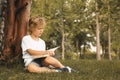 Cute little boy reading book on green grass near tree Royalty Free Stock Photo