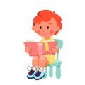 Cute little boy reading book, happy child with red hair sitting on chair to read, study Royalty Free Stock Photo