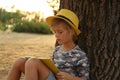 Cute little boy reading book near tree in park Royalty Free Stock Photo