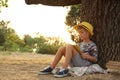 Cute little boy reading book near tree in park Royalty Free Stock Photo