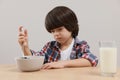 Cute little boy refusing to eat his breakfast at table on grey background Royalty Free Stock Photo