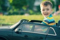 Cute little boy in riding a black electric car in the park